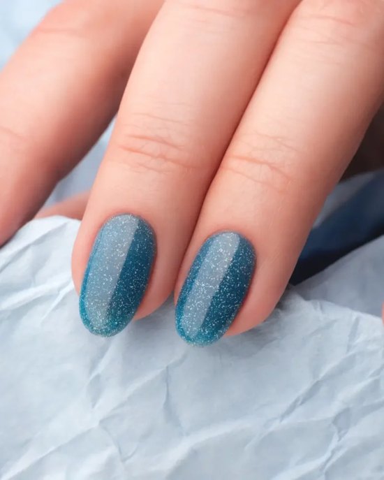 Hand with teal acrylic nails resting on a grey knit.