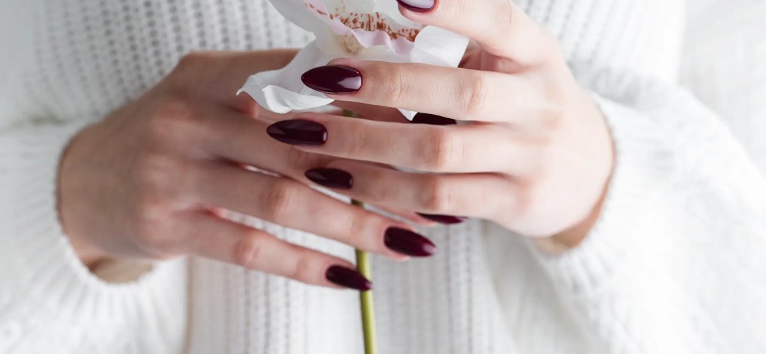Hand with deep red acrylic manicure.