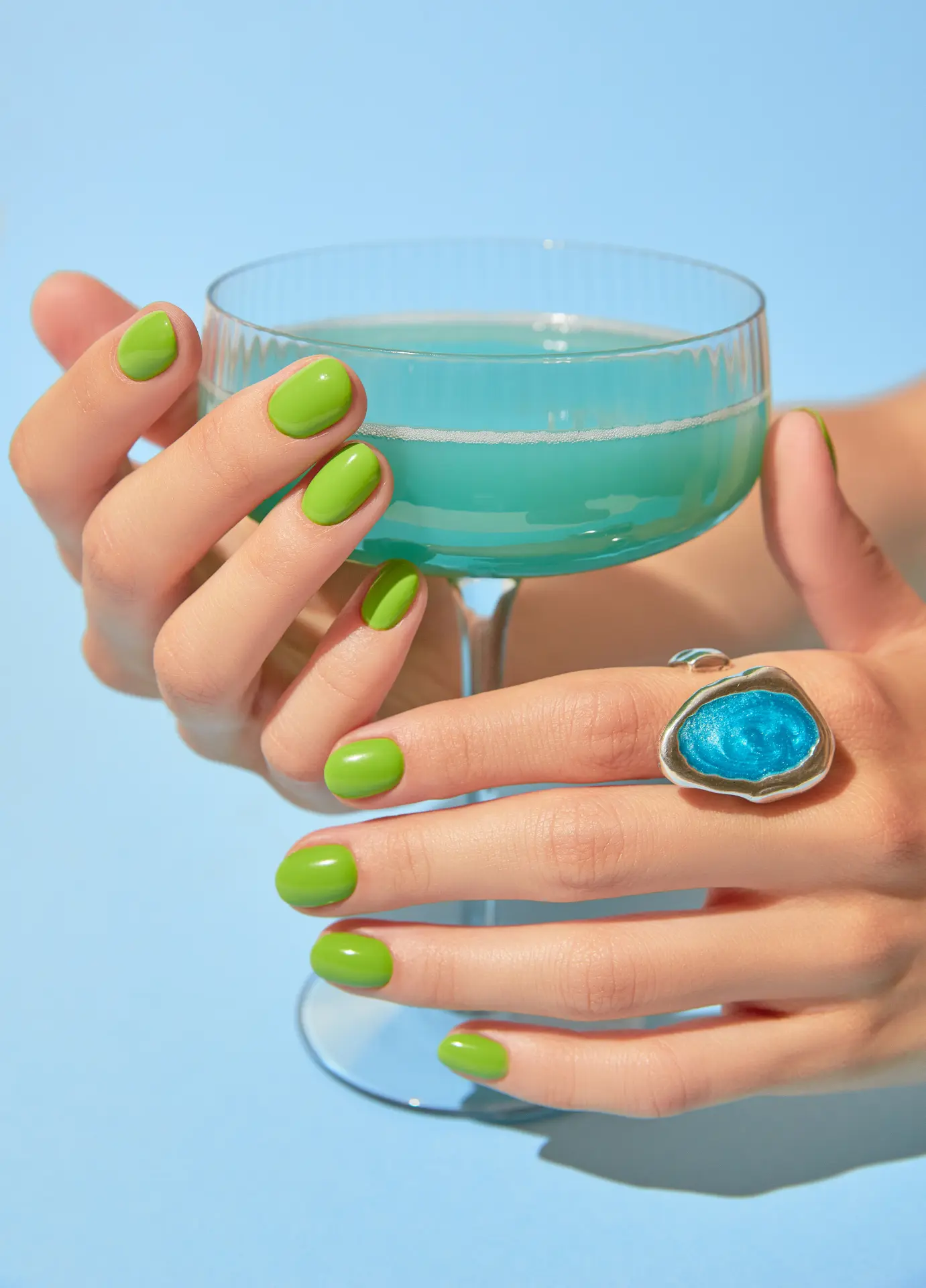 Hand with summer-green bio gel nails holding a glass.