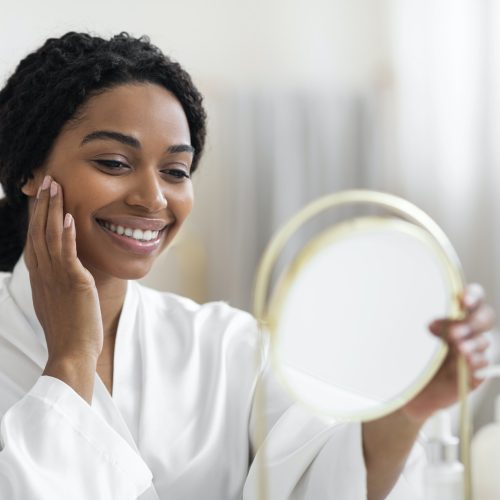 Attractive Black Woman Looking At Mirror And Touching Perfect Skin On Face