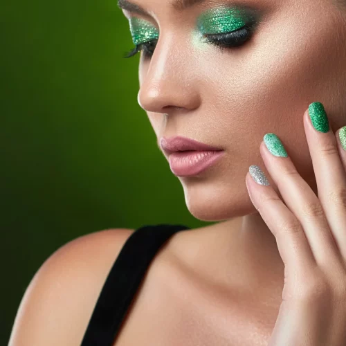 Woman with green glitter makeup and nail polish.
