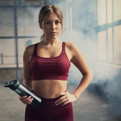 Woman in gym wear holding water bottle.