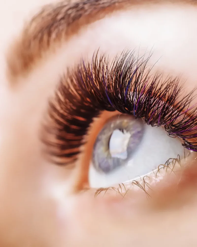 Eyelash Extensions Procedure. Woman Eye with Long Eyelashes. Close up, selective focus