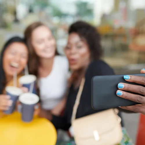 Friends taking selfie with coffee at cafe.
