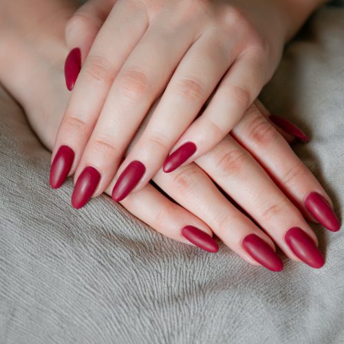 Model woman showing red shellac manicure on long nails