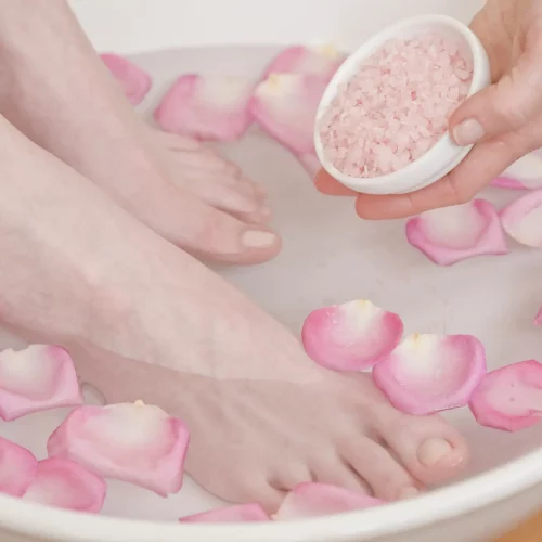 Feet soaking in petal bath with pink salts.
