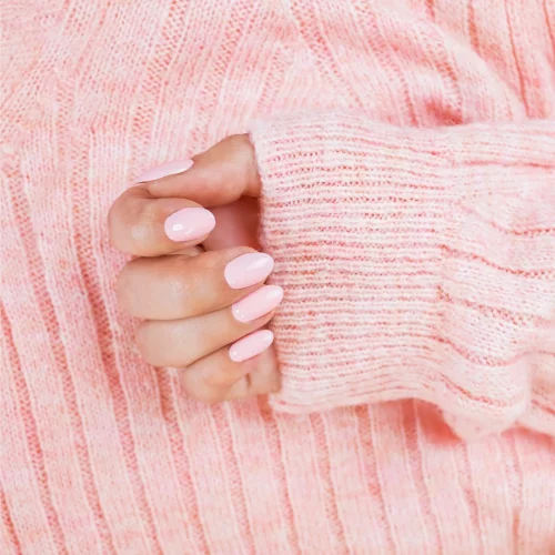 Hand with pink manicure and cozy sweater.
