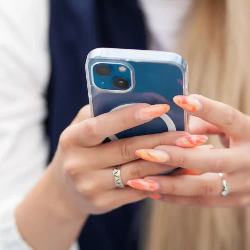 Person texting on smartphone with colorful nails.